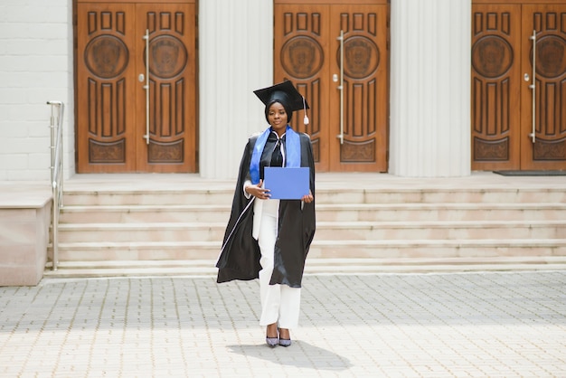 Vrij Afro-Amerikaanse vrouwelijke afgestudeerde buiten universiteitsgebouw