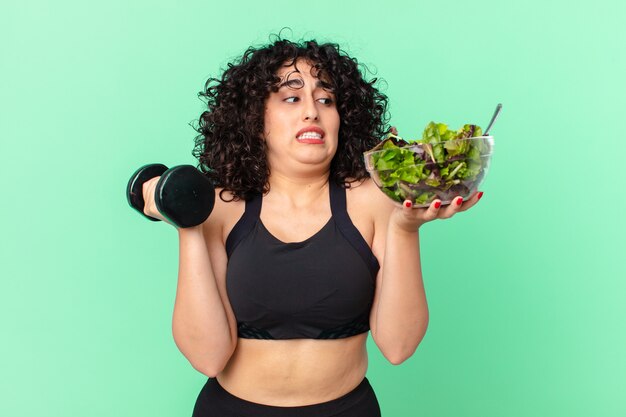 Vrij Arabische vrouw met een halter en een salade. fitness concept