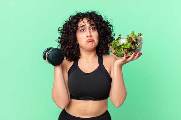 Vrij Arabische vrouw met een halter en een salade. fitnessconcept