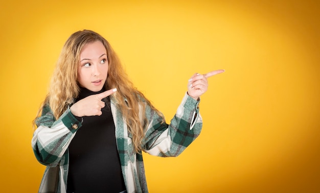 Foto vrij blanke vrouw, gekleed in vrijetijdskleding, wijst naar haar rechter kopie ruimte fodo geel