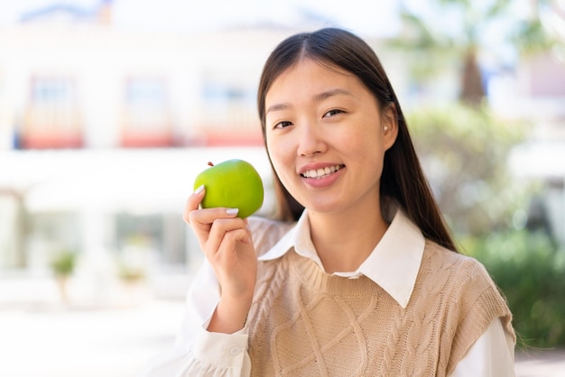 Vrij Chinese vrouw die in openlucht een appel met gelukkige uitdrukking houdt