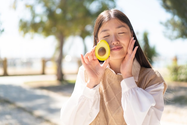 Vrij Chinese vrouw die in openlucht een avocado houdt