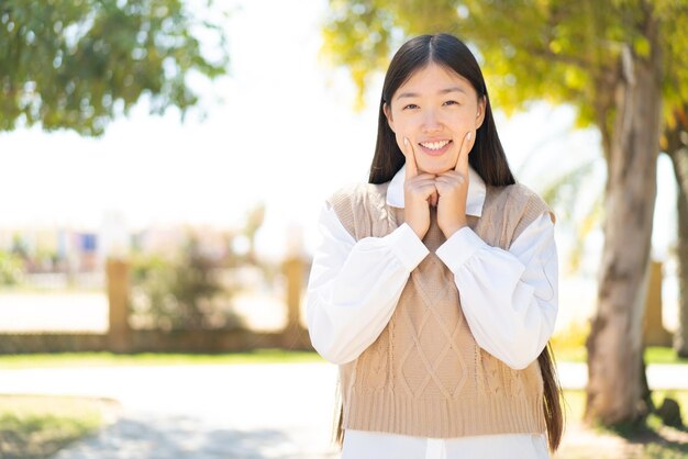 Vrij Chinese vrouw die in openlucht glimlacht met een gelukkige en aangename uitdrukking