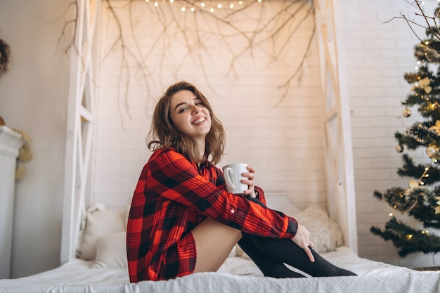 Foto vrij donkerbruin meisje in bed dat rood overhemd en warme sokken draagt