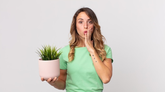 Vrij dunne vrouw die geschokt en bang is en een decoratieve plant vasthoudt