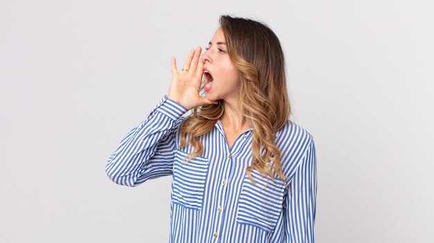 Vrij dunne vrouw die luid en boos schreeuwt om ruimte aan de zijkant te kopiëren, met hand naast mond