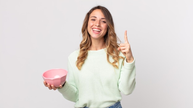 Vrij dunne vrouw die zich een gelukkig en opgewonden genie voelt nadat ze een idee heeft gerealiseerd en een lege potkom vasthoudt