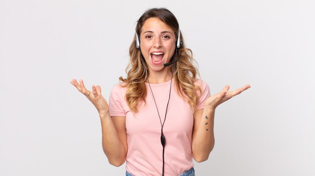 Vrij dunne vrouw die zich gelukkig en verbaasd voelt over iets ongelooflijks. Operator-assistent met een headset