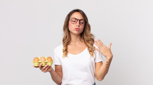 Vrij dunne vrouw die zich gestrest, angstig, moe en gefrustreerd voelt en een eierdoos vasthoudt