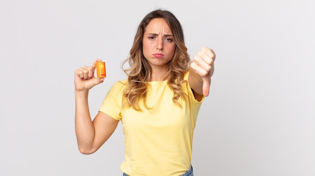 Vrij dunne vrouw die zich kruis voelt duimen naar beneden en batterijen vasthoudt