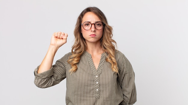 Vrij dunne vrouw die zich serieus, sterk en rebels voelt, vuist opheft, protesteert of vecht voor revolutie