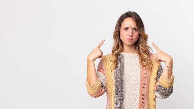 Vrij dunne vrouw met een slechte houding die er trots en agressief uitziet, naar boven wijst of een grappig teken maakt met handen