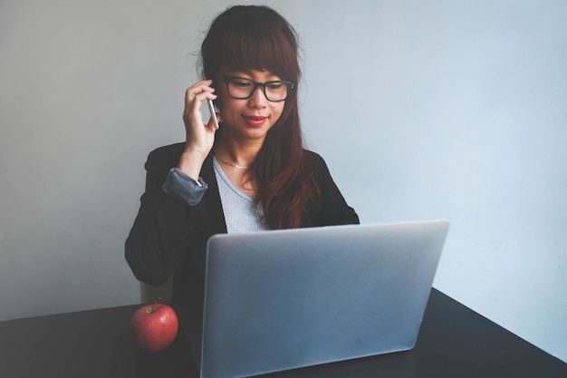 Vrij glimlachende bedrijfsvrouw die celtelefoon en notitieboekje gebruiken