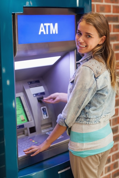 Foto vrij glimlachende student die contant geld terugtrekt