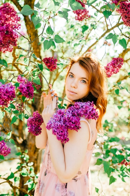 Vrij het donkerbruine vrouw stellen in bloeiende bloemen.