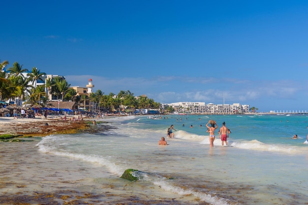 Vrij jong meisje in sexy Braziliaanse bikini loopt en draagt haar tas langs het strand met golven