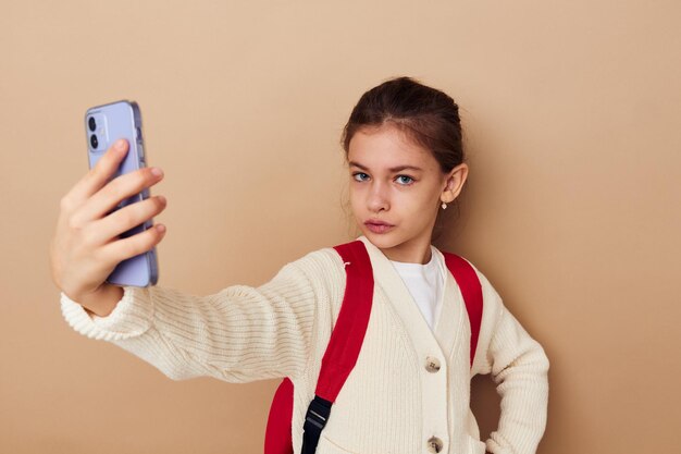 Vrij jong meisje schoolmeisje rugzak telefoon in de hand kinderjaren ongewijzigd