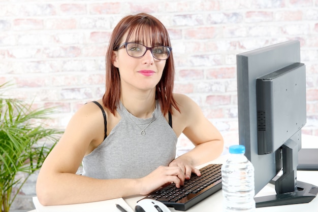 Vrij jonge bedrijfsvrouw die bij PC in bureau werkt