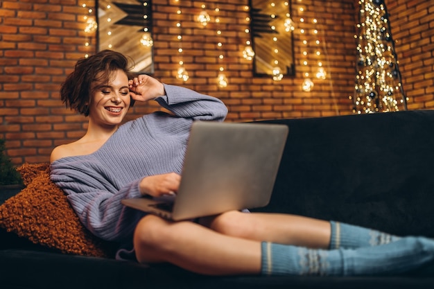 Vrij jonge brunette thuis op de laag die laptop met behulp van