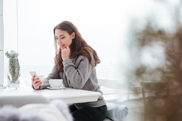 Vrij jonge dame die koffie drinkt terwijl het telefoneren