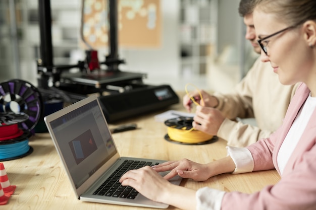 Vrij jonge ontwerper die laptopvertoning bekijkt terwijl hij over nieuwe schetsen werkt