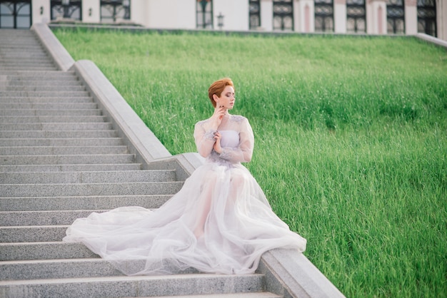 Vrij jonge roodharige vrouw in een tuin en buiten met haar trouwjurk