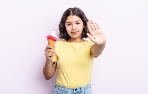 Vrij jonge vrouw die ernstig kijkt die open palm toont die stopgebaar maakt. ijs concept