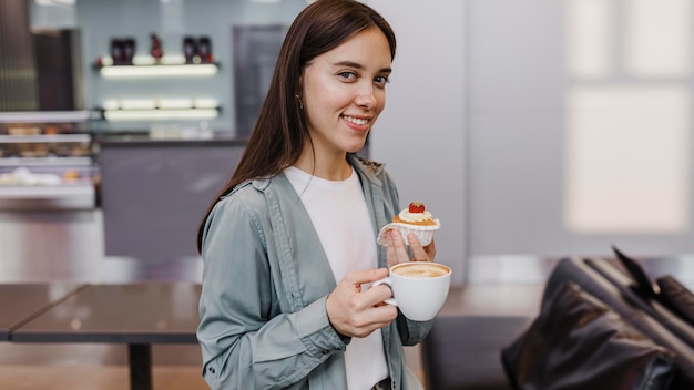 Foto vrij jonge vrouw die van een koffie en cake geniet