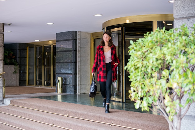 Vrij jonge vrouw die verlatend een Hotel loopt dat de herfst elegante kleren draagt