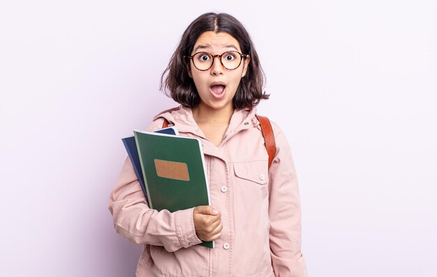 Vrij jonge vrouw die zeer geschokt of verrast kijkt. student met boeken concept