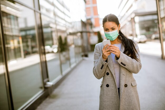 Vrij jonge vrouw met beschermend gezichtsmasker op straat