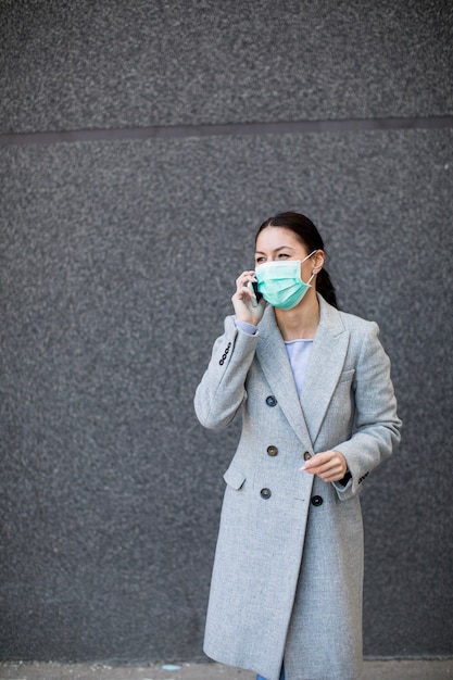 Vrij jonge vrouw met beschermend gezichtsmasker op straat