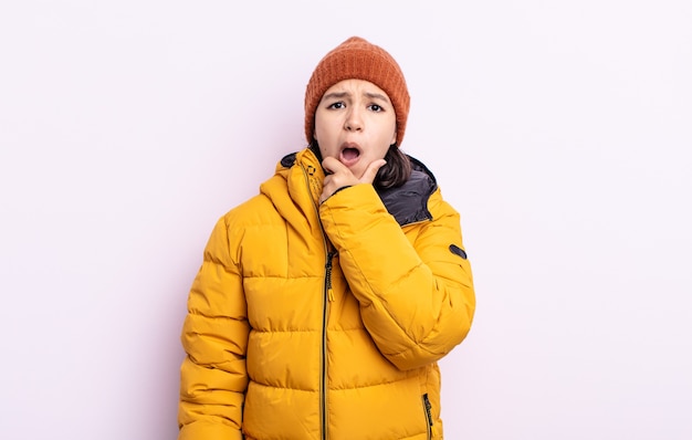 Vrij jonge vrouw met wijd open mond en ogen en hand op kin. koud weer concept