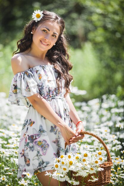 Vrij jonge vrouw op het gebied van kamille. Mooi meisje met bloemen