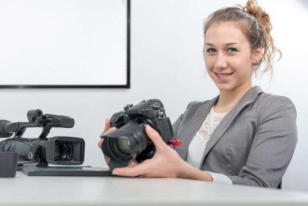 Vrij jonge vrouwenfotograaf met camera in bureau