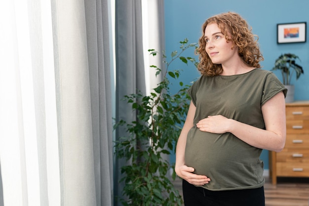 Vrij jonge zwangere vrouw die zich door het venster in ruimte bevindt