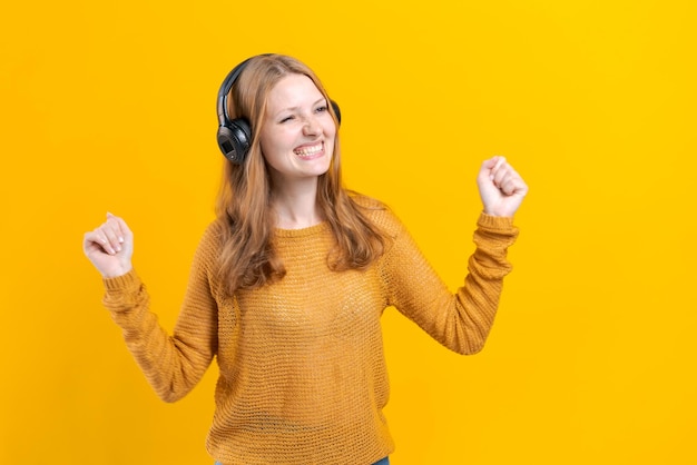 Vrij Kaukasisch meisje in gele trui luisteren naar muziek op een mobiele telefoon