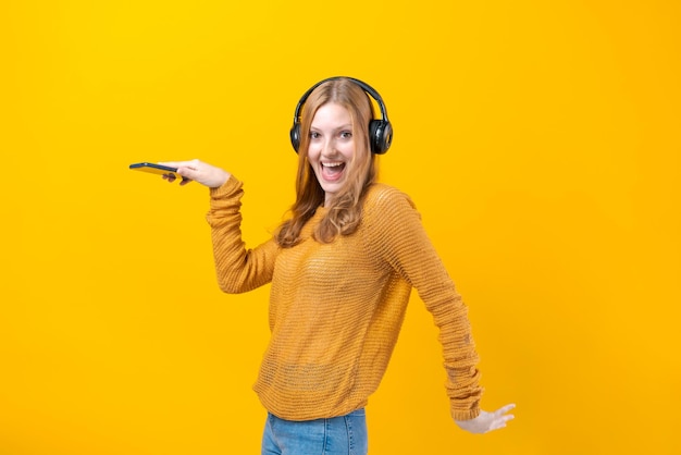 Vrij Kaukasisch meisje in gele trui luisteren naar muziek op een mobiele telefoon