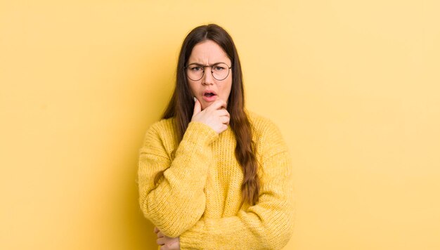 Vrij kaukasische vrouw met wijd open mond en ogen en hand op kin die zich onaangenaam geschokt voelt en zegt wat of wauw