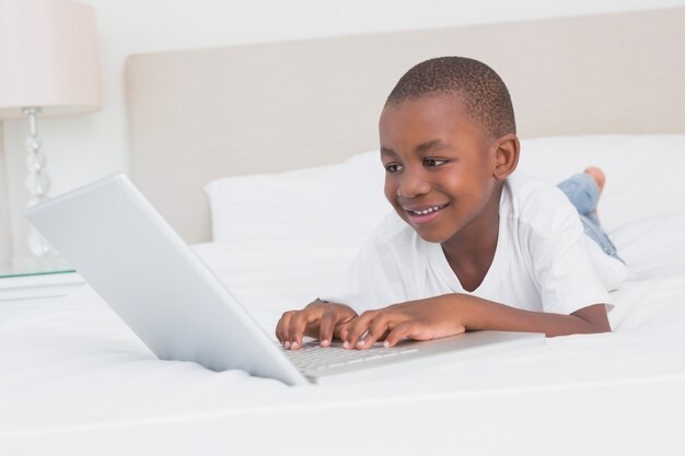 Vrij kleine jongen die laptop in bed met behulp van