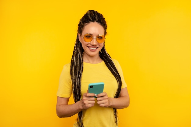 Vrij lachende jonge vrouw met dreadlocks poseren met mobiele geïsoleerd.