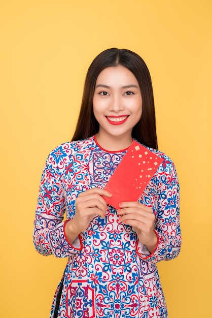 Vrij lachende Vietnamese vrouw met rode enveloppen geïsoleerd op gele achtergrond