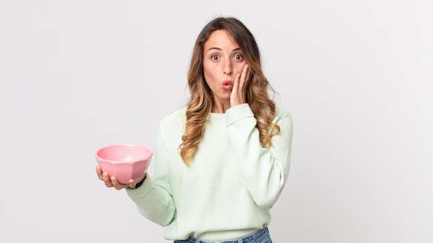 Vrij magere vrouw die geschokt en bang is en een lege pottenkom vasthoudt