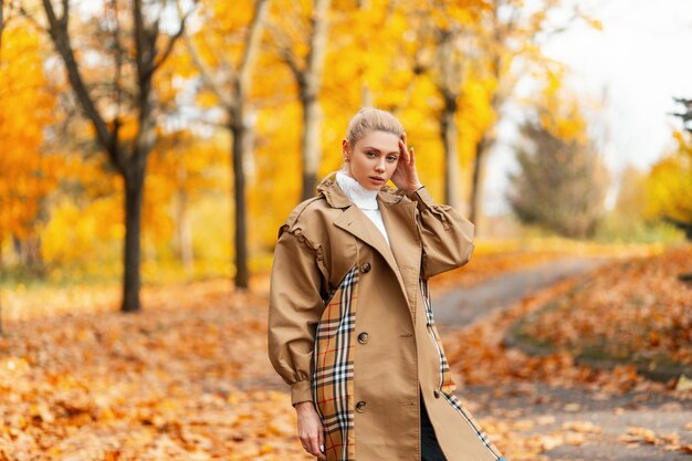 Vrij mooi jong vrouwenmodel in een trendy beige jas met een stijlvol kapsel