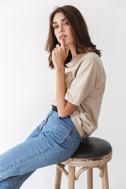 vrij mooie jonge brunette vrouw poseren binnenshuis geïsoleerd over witte muur achtergrond.