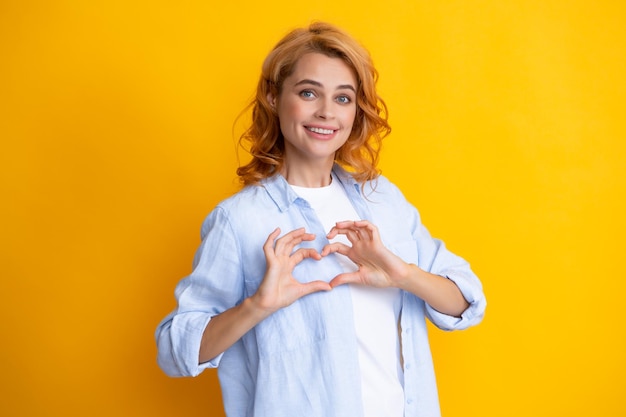 Vrij romantische jonge vrouw die een hartgebaar maakt dat liefde en affectie toont dankbaar gebaar met een gelukkige tedere glimlach De liefde van meisjesgevoelens Mooie vrouw met het symbool van het hartteken