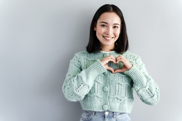 Vrij romantische jonge vrouw maakt een hart uit haar vingers