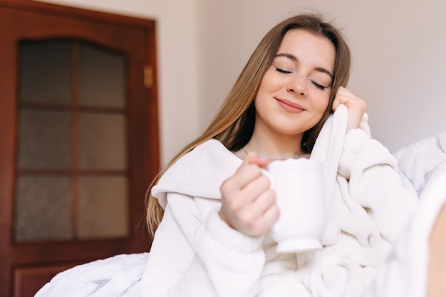 Vrij schattig meisje drinkt thuis koffie uit een witte kop