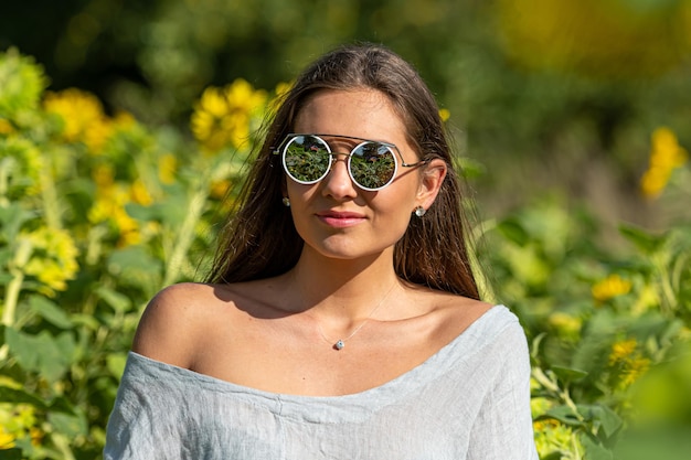 Vrij sensuele jonge brunette in zonnebril in een veld van bloeiende zonnebloemen jonge vrouw portret