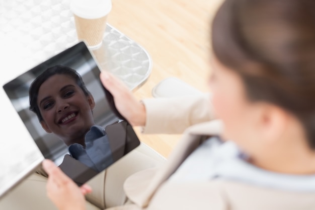 Vrij slimme bruine haired onderneemster die een tabletpc houdt